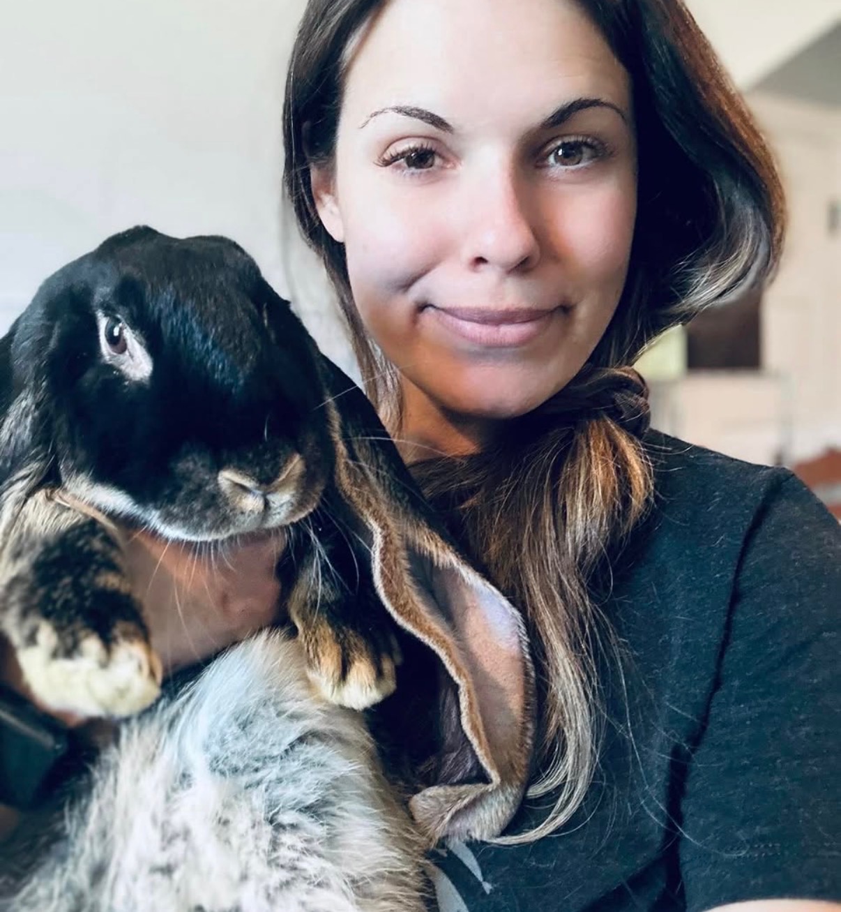 Founder Nik smiling while holding a black-and-tan lop-eared rabbit